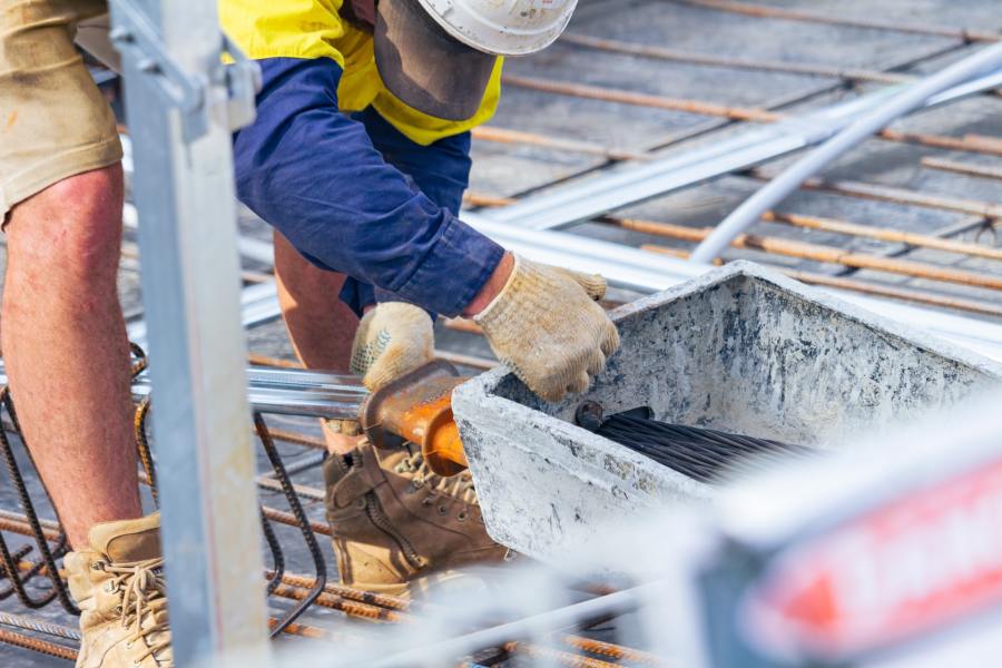 A builder laying concrete foundations on a work site.