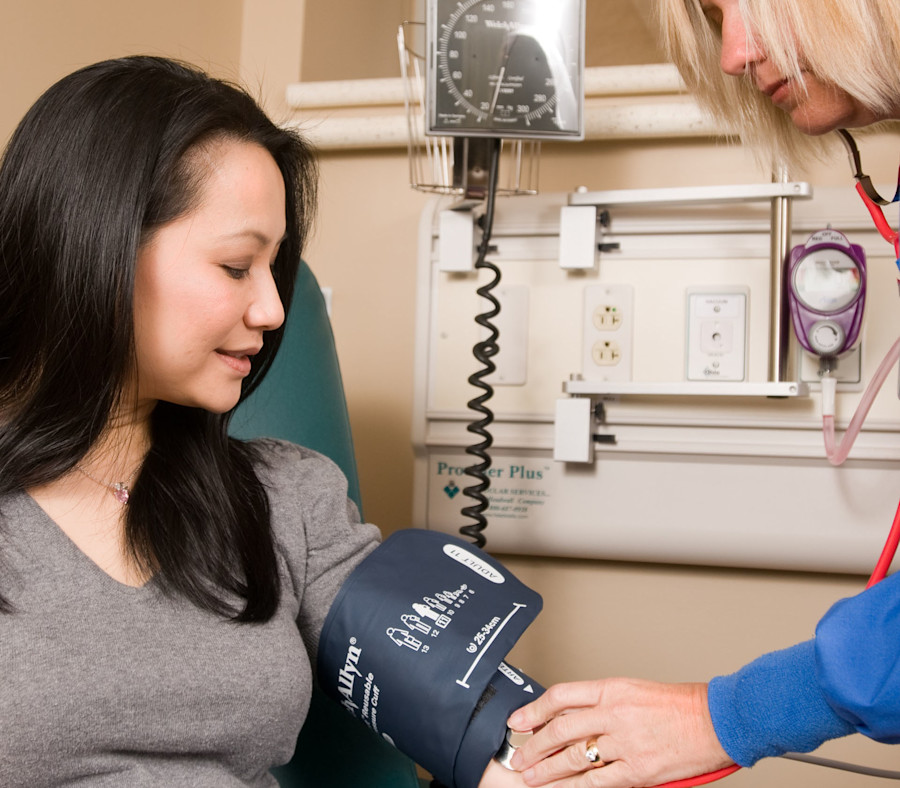 Woman getting her blood pressure checked by a health care professional.