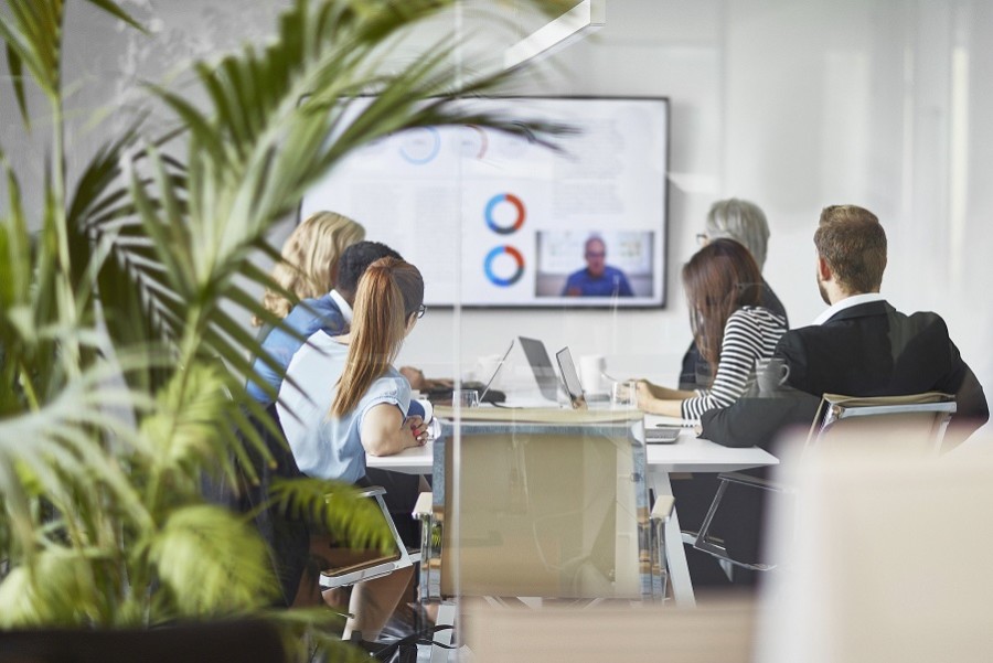 Colleagues sitting around a boardroom table watching a presentation. 