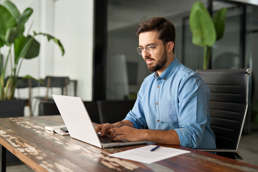 Man sitting at a desk using a laptop computer.