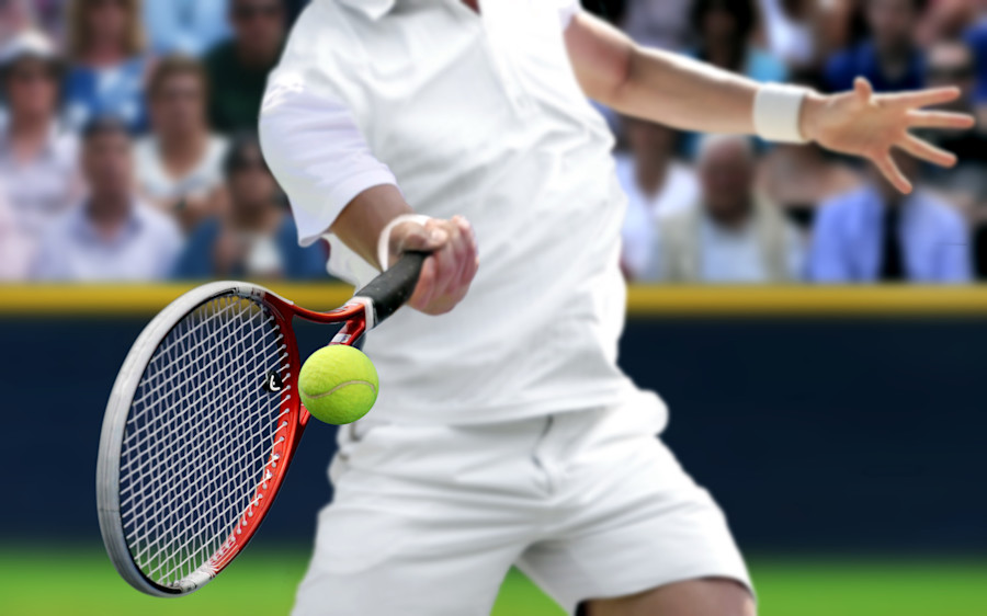 Male tennis player hitting a tennis ball with a tennis racquet.