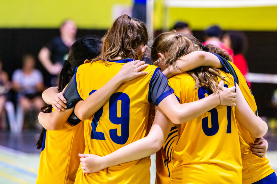 A women's volleyball team pictured in a huddle.