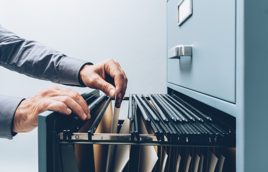 Person looking through a filing cabinet containing documents.