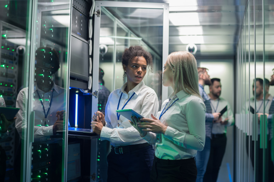 Two women standing in a data centre or communications room 