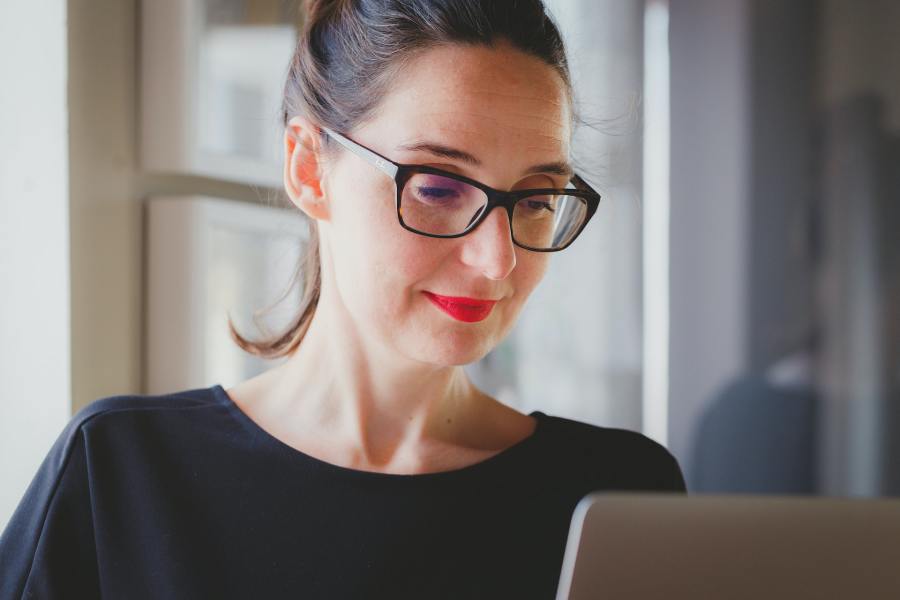 Close-up image of a professional women wearing glasses, working on a laptop.