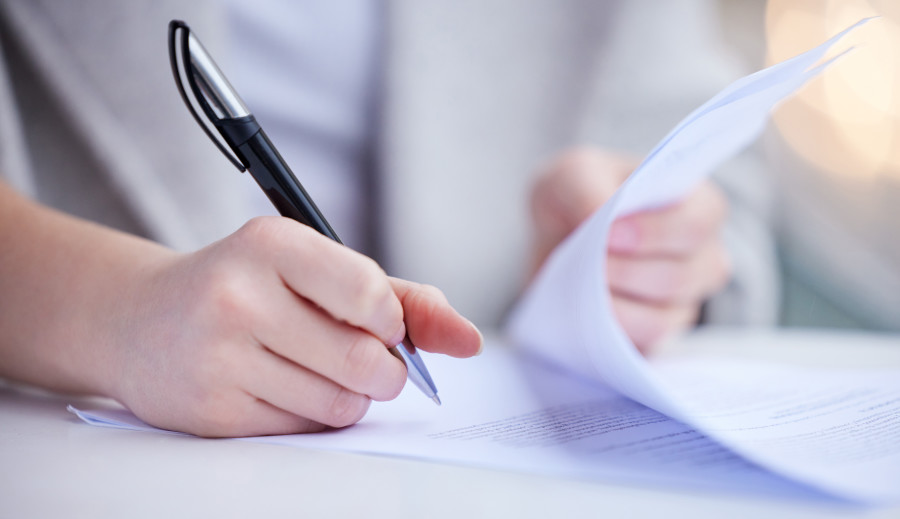 An arm and hand holding a pen ready to sign a contract