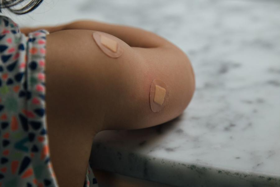A child with a plaster on their arm following a vaccination dose.
