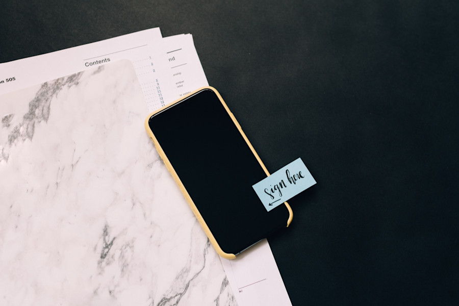 Documents and mobile phone ready to be used to sign and witness a company document.