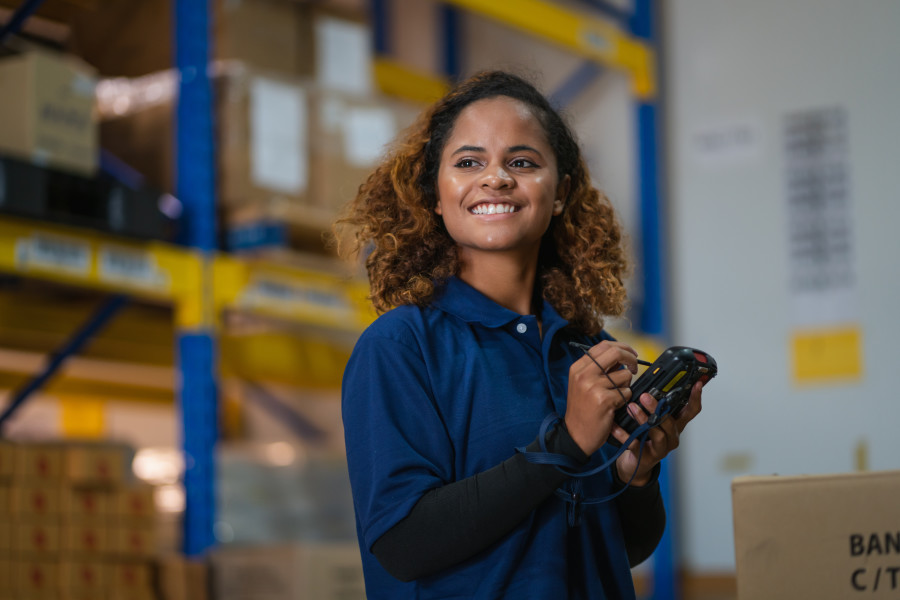 A woman recording or tracking stock in a warehouse or distribution facility.  