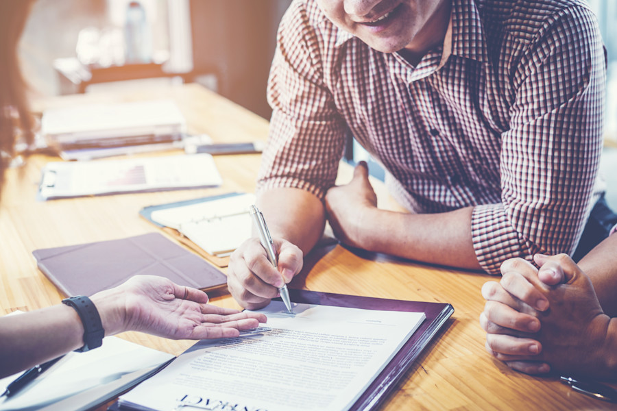 Three people sitting around a desk discussing a contract or loan agreement.