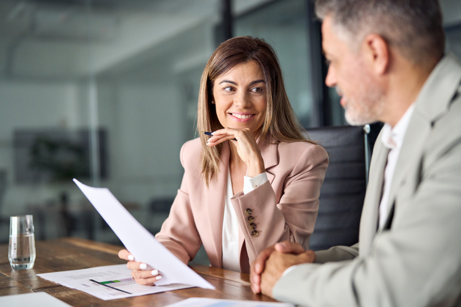 Female and male business executive or lawyer sitting at a table in an office discussing a document.