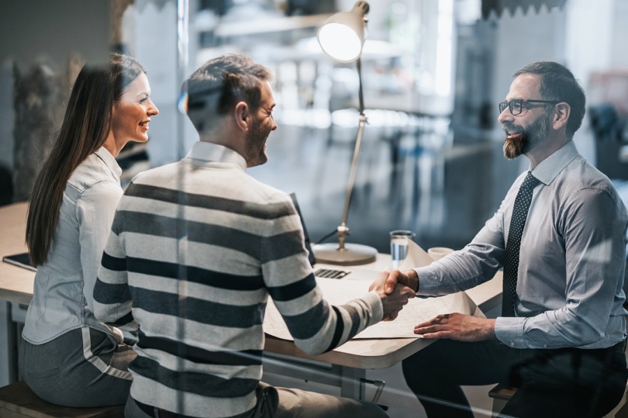 Two men shaking hands at an office table.