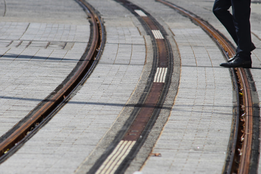 Person walking across light rail tracks in the road in Sydney