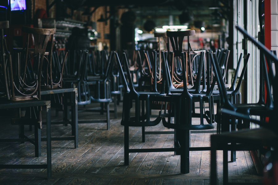 Interior shot of a cafe or restaurant. The stools and chairs have been stacked on top of the tables and the place is dark and empty. 