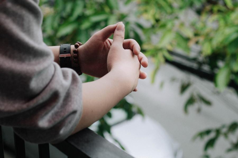 Person quietly reflecting with hands clasped together.