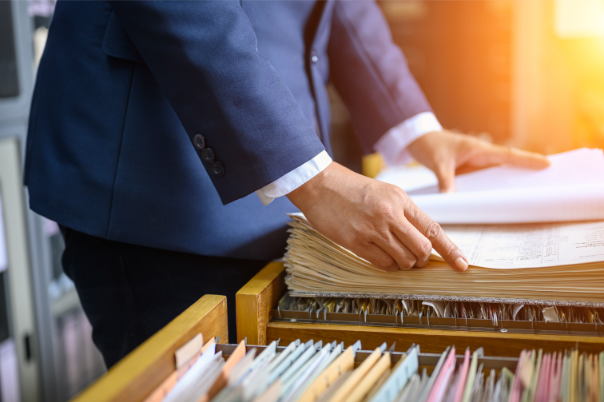 Man in suit looks through file of documents in an office.