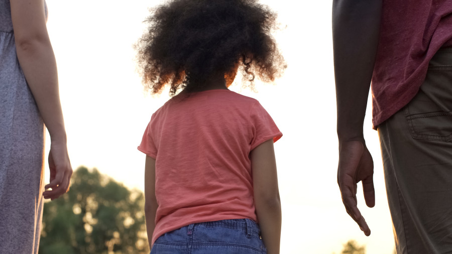 Child standing between two parents.