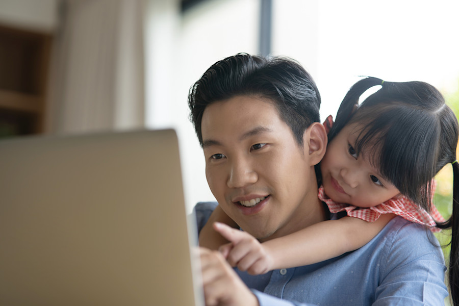 Father and daughter looking at something on a laptop screen.