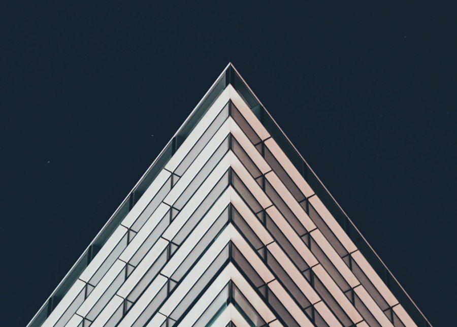 A corner of a white and grey patterned building set against a dark blue/grey background. 