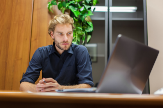 Man looking at a laptop with a concerned expression.