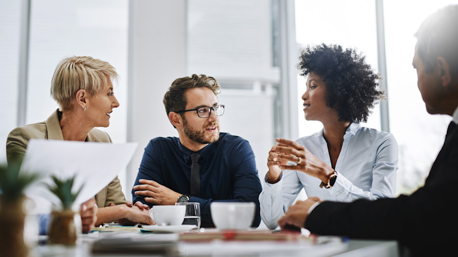 Professional workers sitting at a desk talking and collaborating 