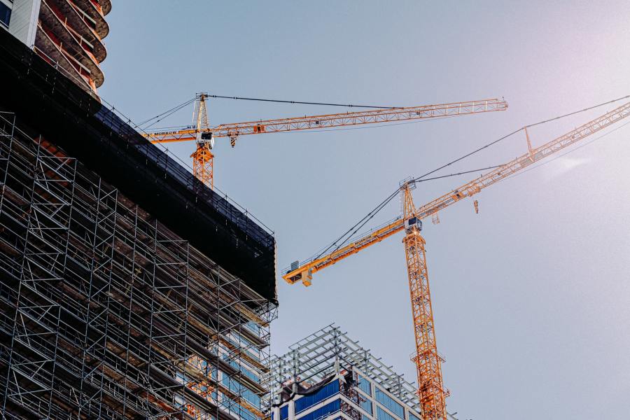 Skyline with top of a commercial building in construction and two yellow cranes.