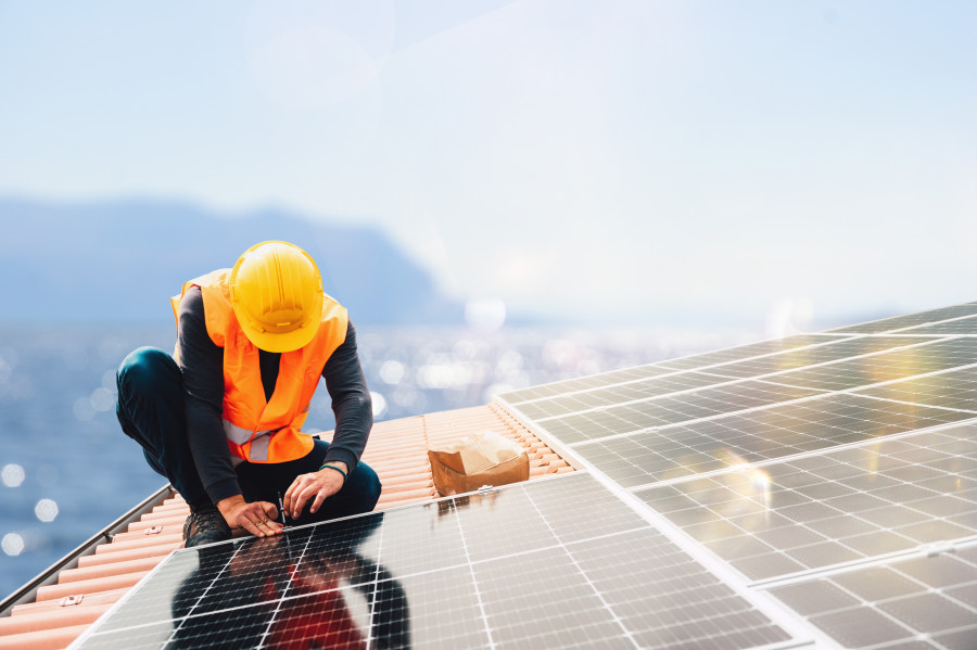 Worker installing solar panels on the roof of a house.