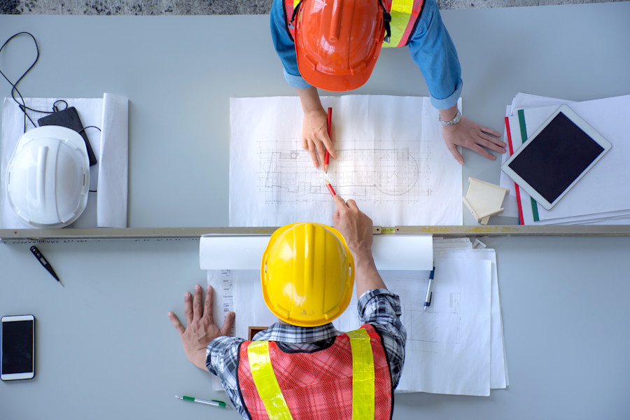 Aerial view of two engineers or building and construction professionals looking at a buliding plan. 