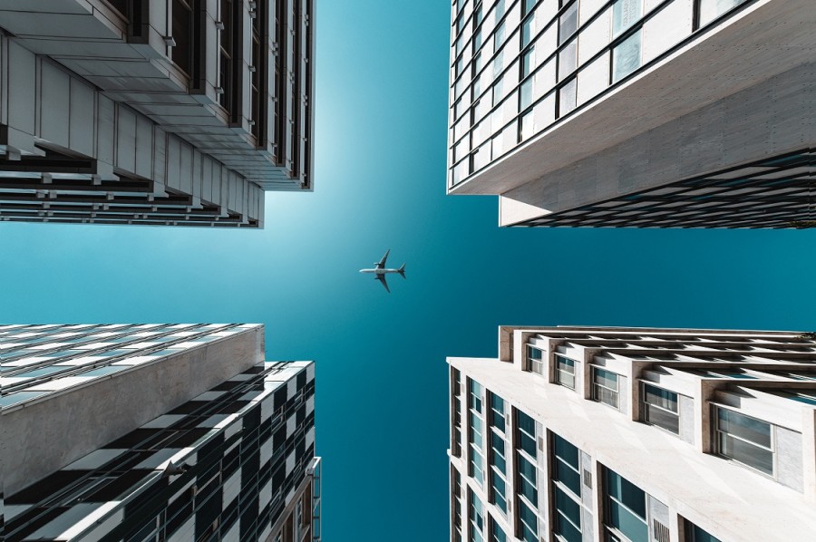 A plane flying over buildings.