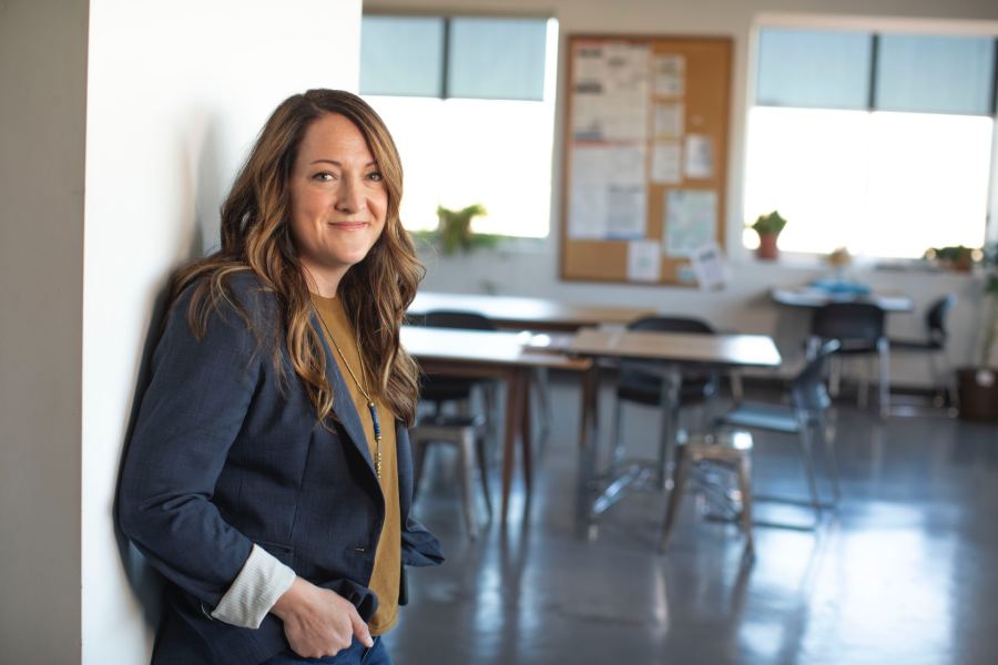 Woman standing in an empty classroom or office space.