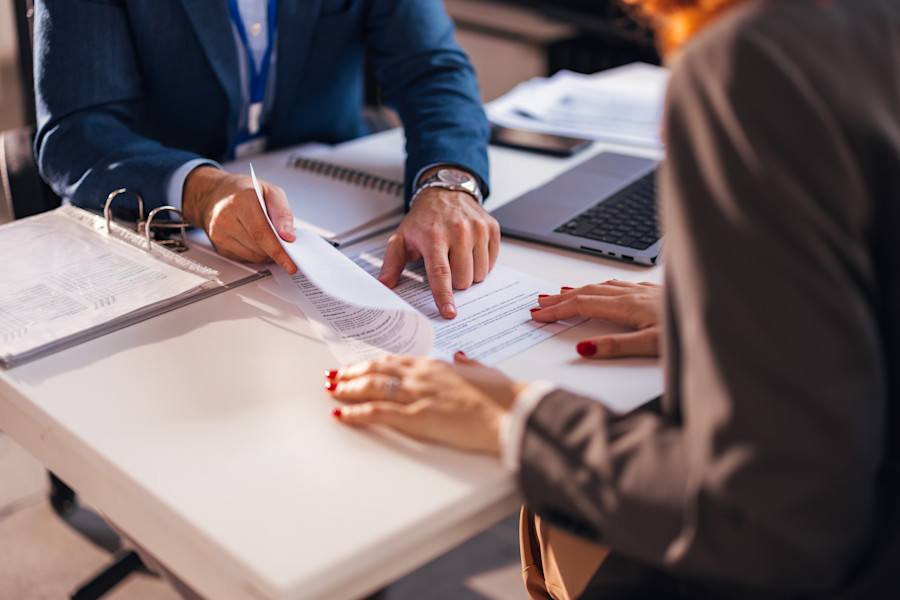 Lawyer and client at an office desk discussing a document. 