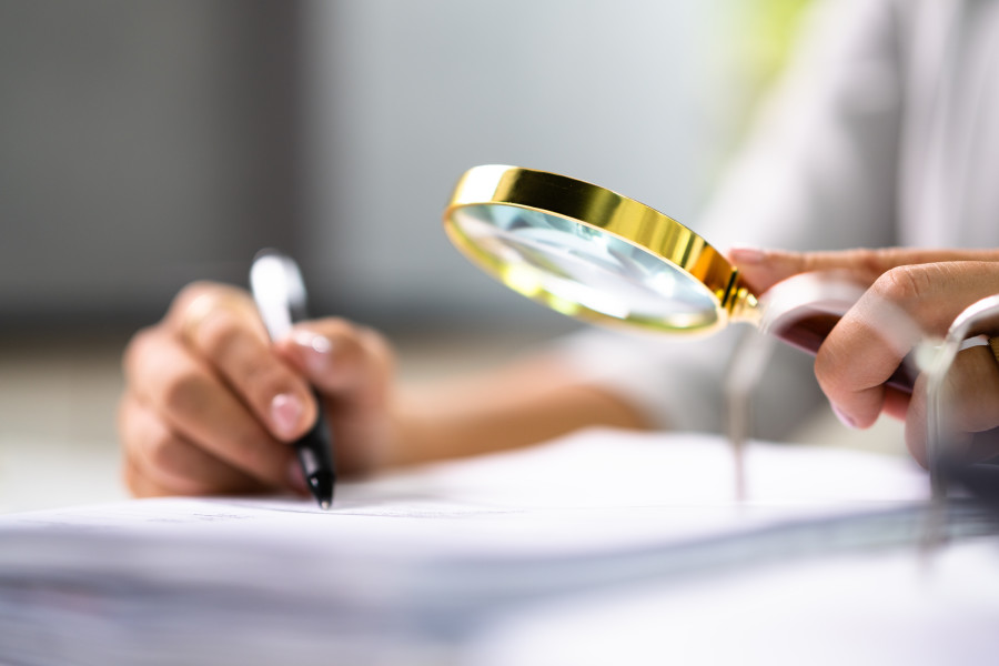 Person reading a document through a magnifying glass, representing a detailed review.