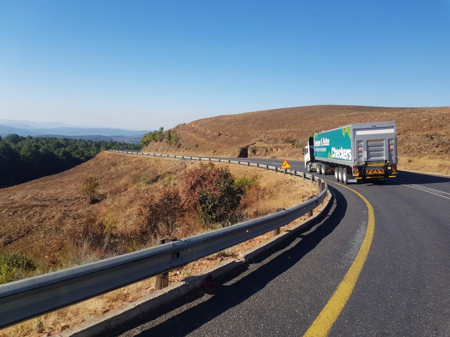 Freighter truck driving on windy country road.