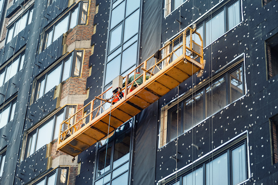 Builders working on the exterior cladding of a high-rise building.