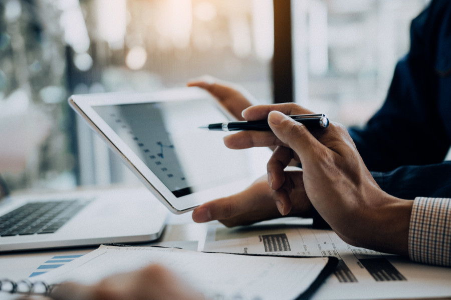 Two people discussing corporate or financial reporting over a tablet or iPad.