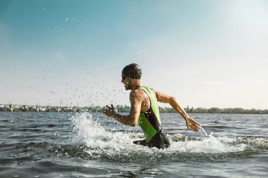 Triathlon athlete running in water on sunny day
