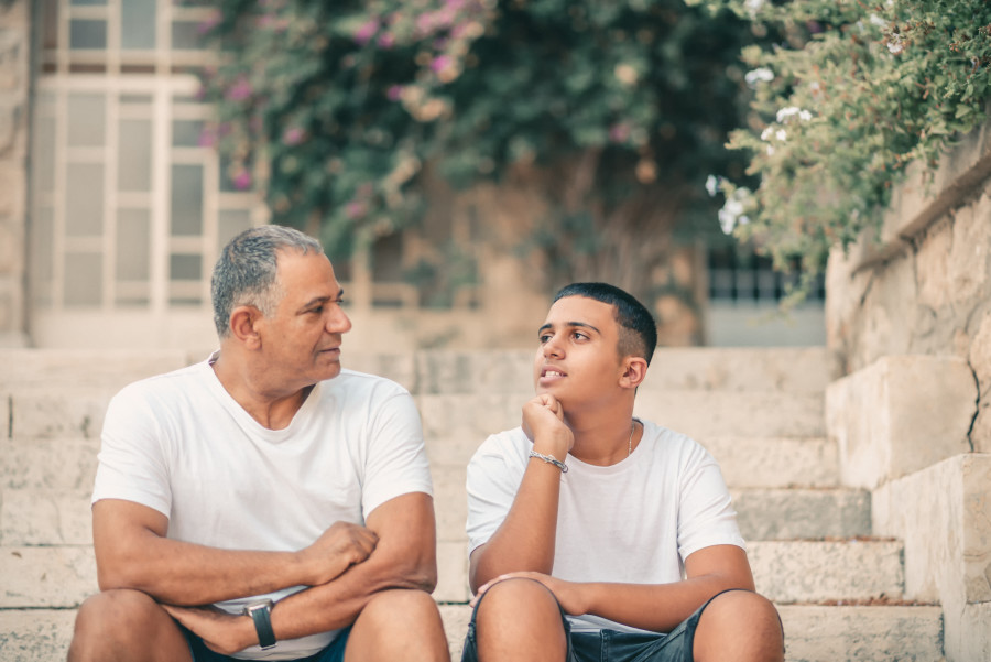 Father and teenage son sitting on a doorstep.