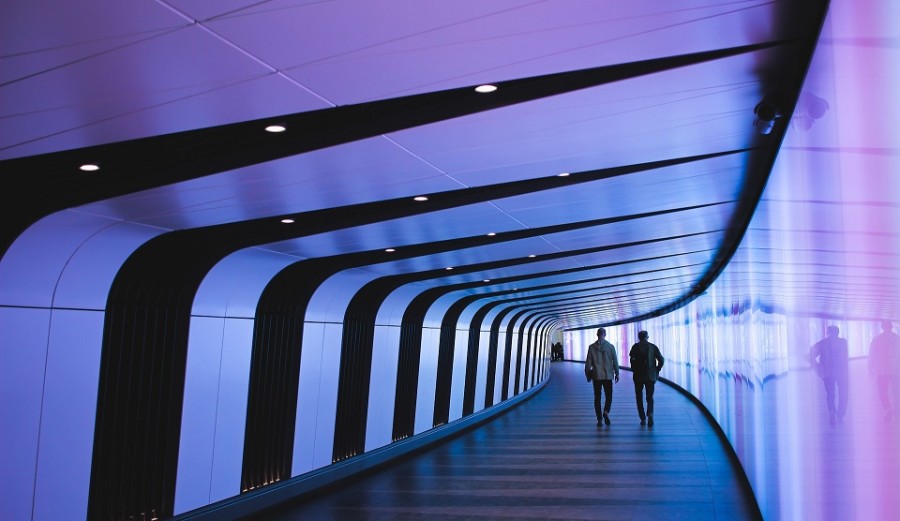 Two people walking in a tunnel.