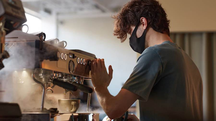 A barista working at a coffee machine in a cafe.