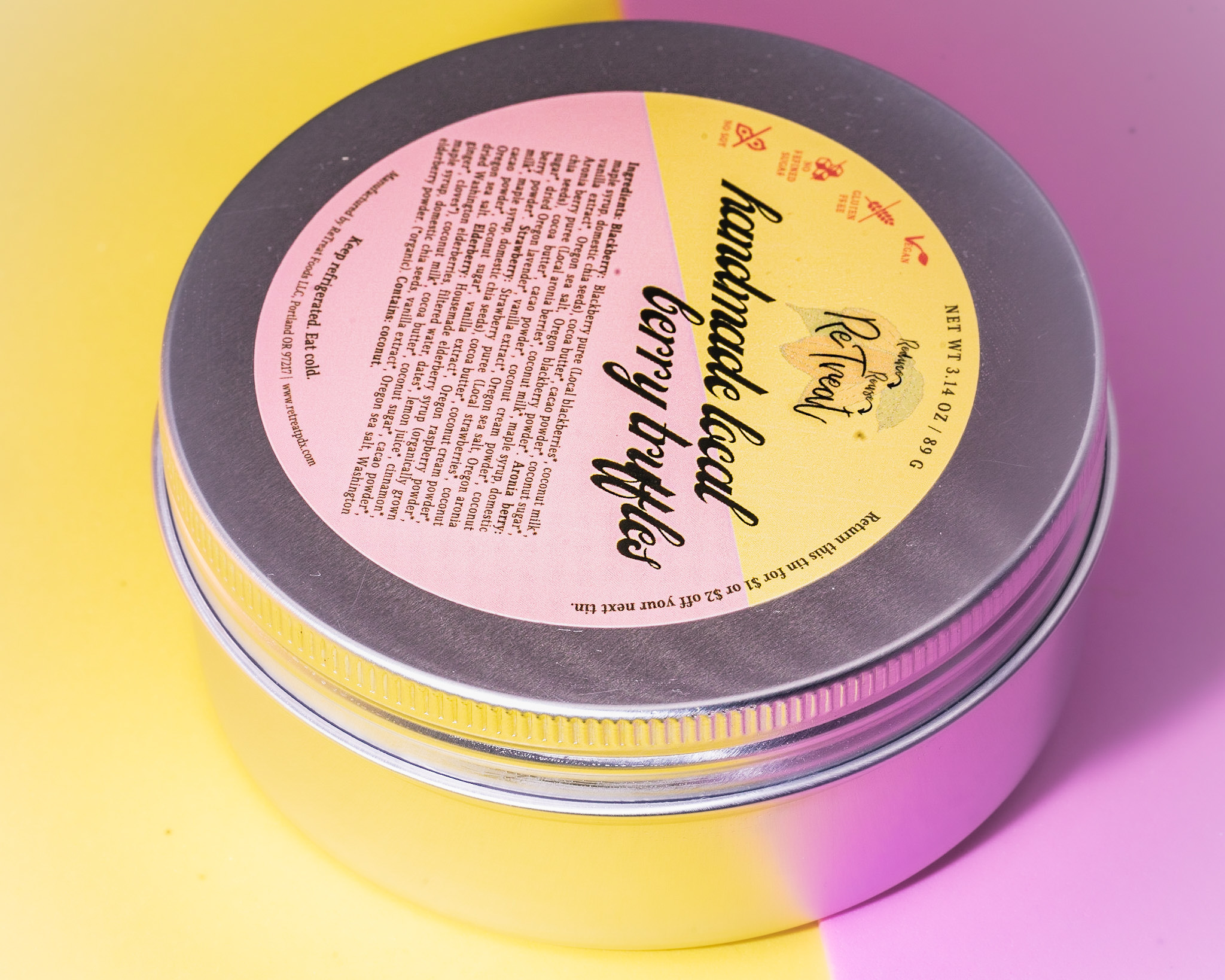 A circular tin with a yellow and pink label sits on a yellow and pink surface