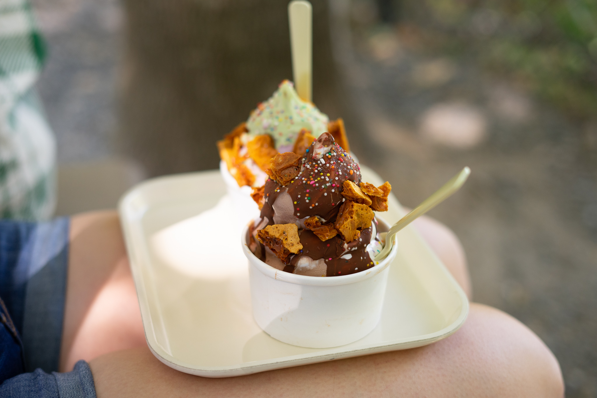 Two ice cream treats with hardened chocolate shells and honeycomb on a white tray.