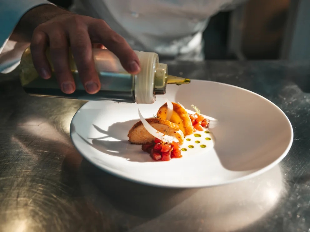A chef decorating a plate of food
