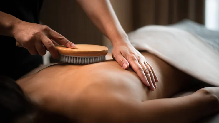 A person giving a back massage using a brush