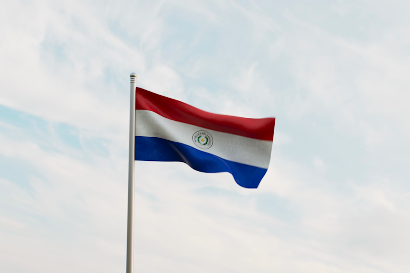 The Paraguayan Flag flying against a backdrop of blue skies and light clouds