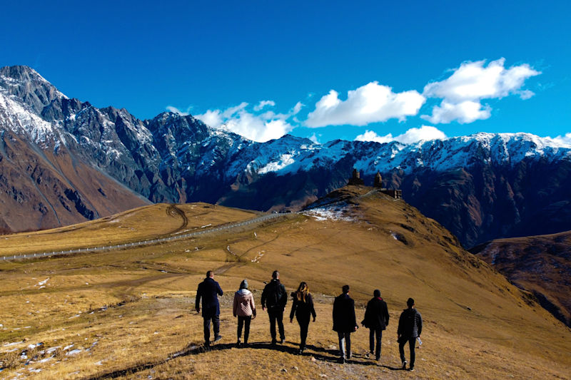 I group of people walking along a mountain top under bright blue skies