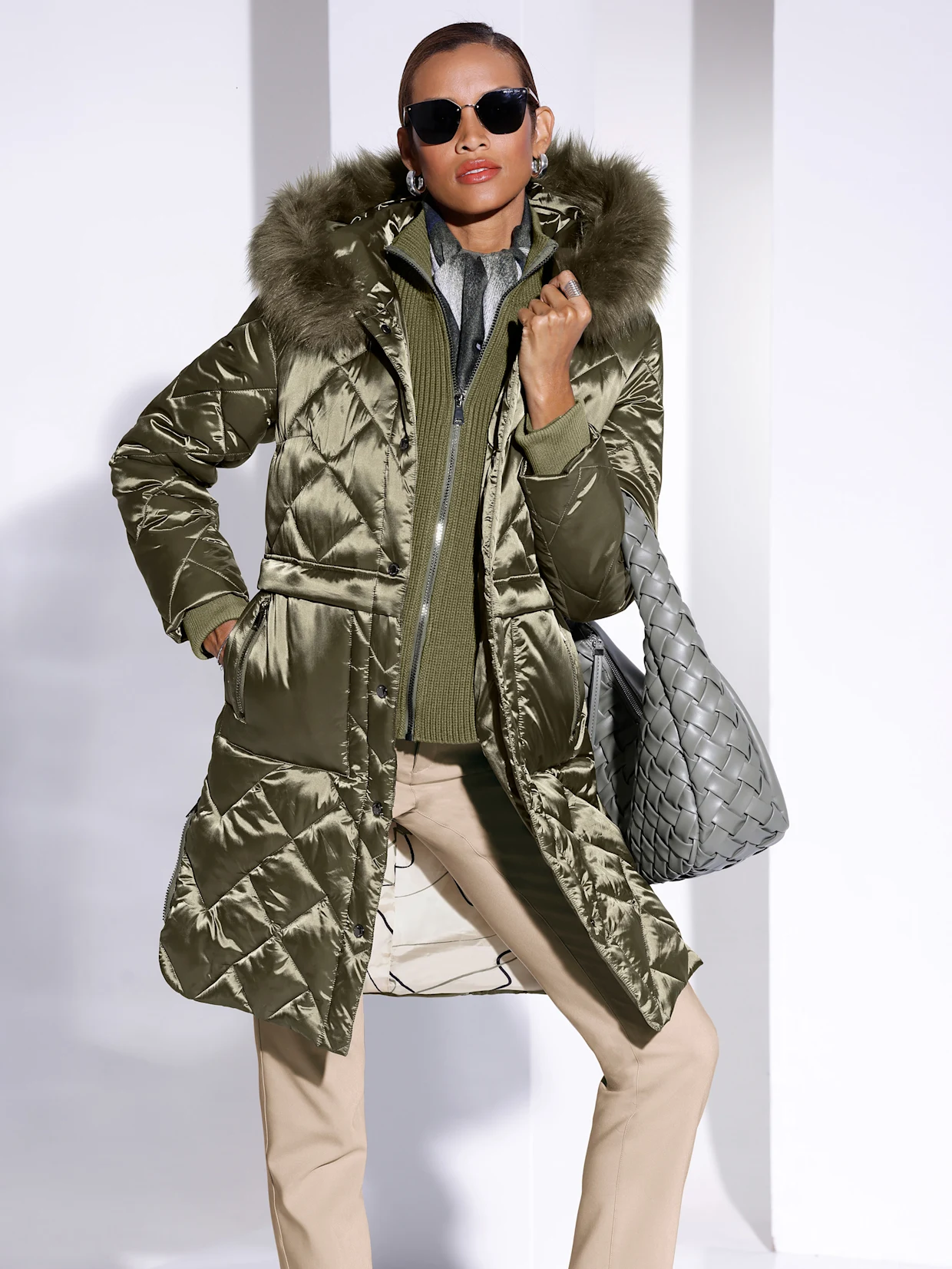 Ein Model trägt eine olivgrüne Jacke mit Pelzkragen und eine graue Tasche, kombiniert mit einem grünen Pullover und beigen Hosen. Ein Model trägt eine olivgrüne Jacke mit Pelzkragen und eine graue Tasche, kombiniert mit einem grünen Pullover und beigen Hosen.