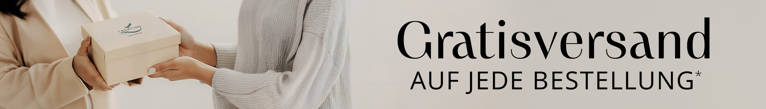 Zwei Personen halten gemeinsam eine beigefarbene Geschenkbox mit CREATION-Logo, Fokus auf die Hände, heller Hintergrund.