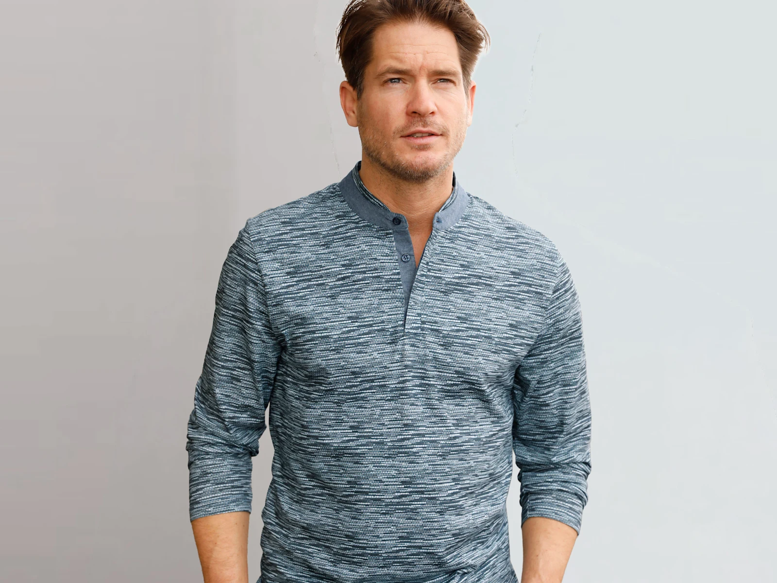 Mann mit blau gemustertem Langarmshirt vor hellem Hintergrund.