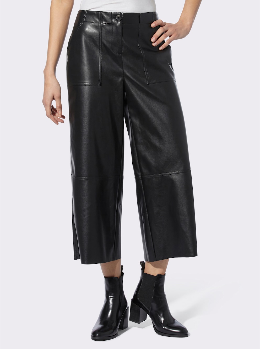 Model trägt eine Lederimitathose im Culotte-Style dazu schwarze Stifeletten.