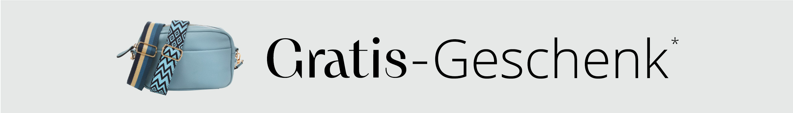 Eine hellblaue Umhängetasche mit zwei verschiedenen gemusterten Tragegurten vor hellem Hintergrund, darüber der Text 'Gratis-Geschenk*'